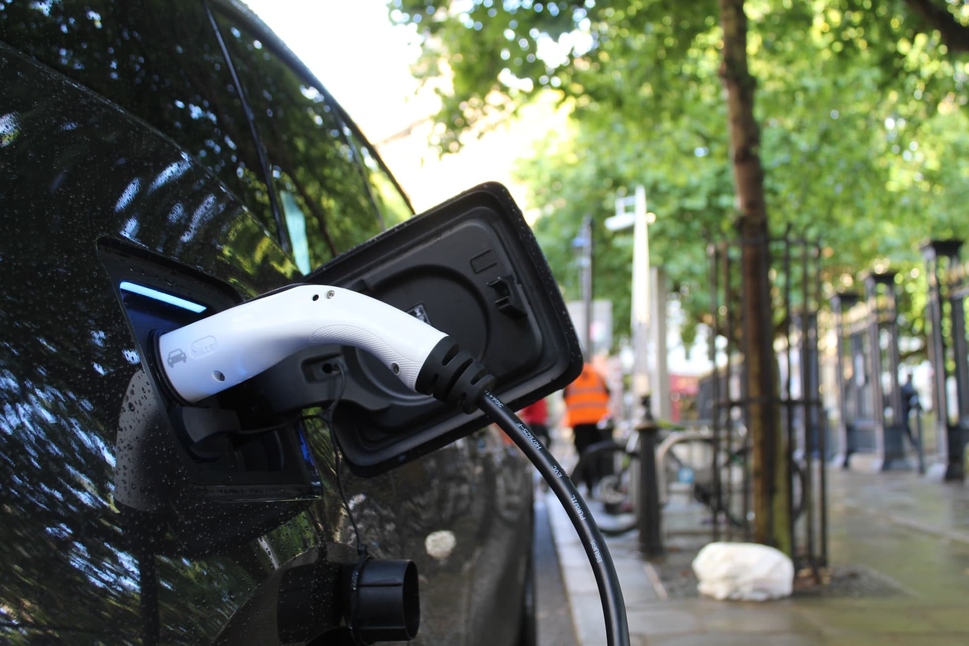 Electric car plugged in on the side of a sunny downtown street